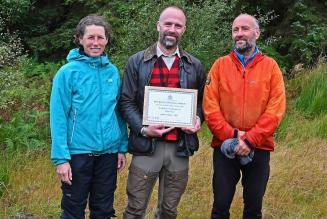 Enduring the Welsh rain, it’s still smiles all round for winners Ruth Pybus, left, and David Brown, right, receiving their joint first place award from FSC UK’s Owen Davies, centre.
